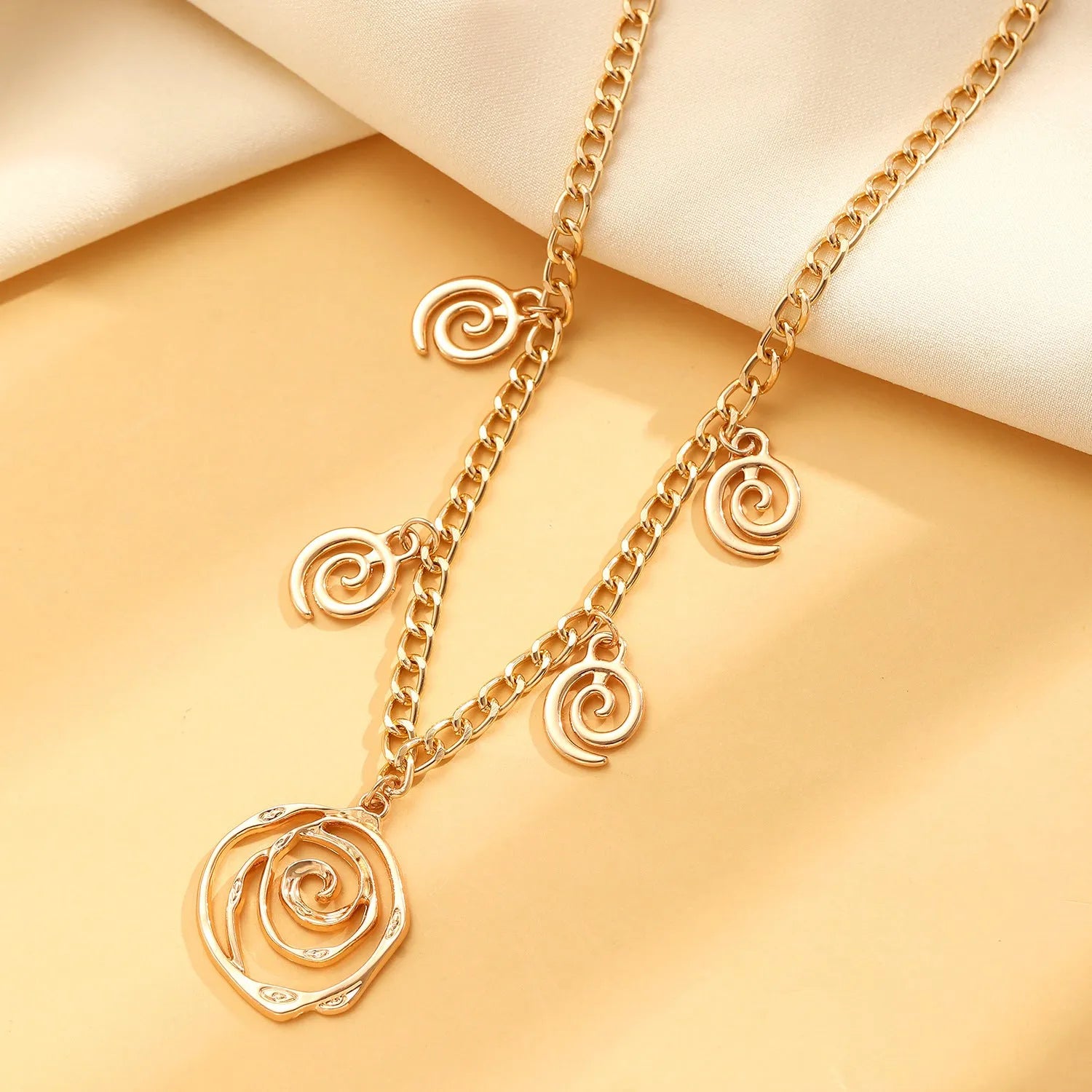 Spiral donut design jewellery set showing necklace, bracelet and ear hooks in gold finish