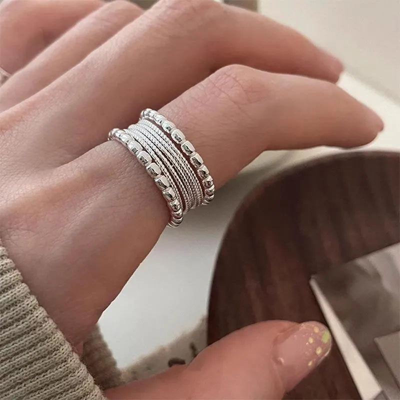 Geometric woven twisted copper alloy ring with an adjustable opening on a neutral background.