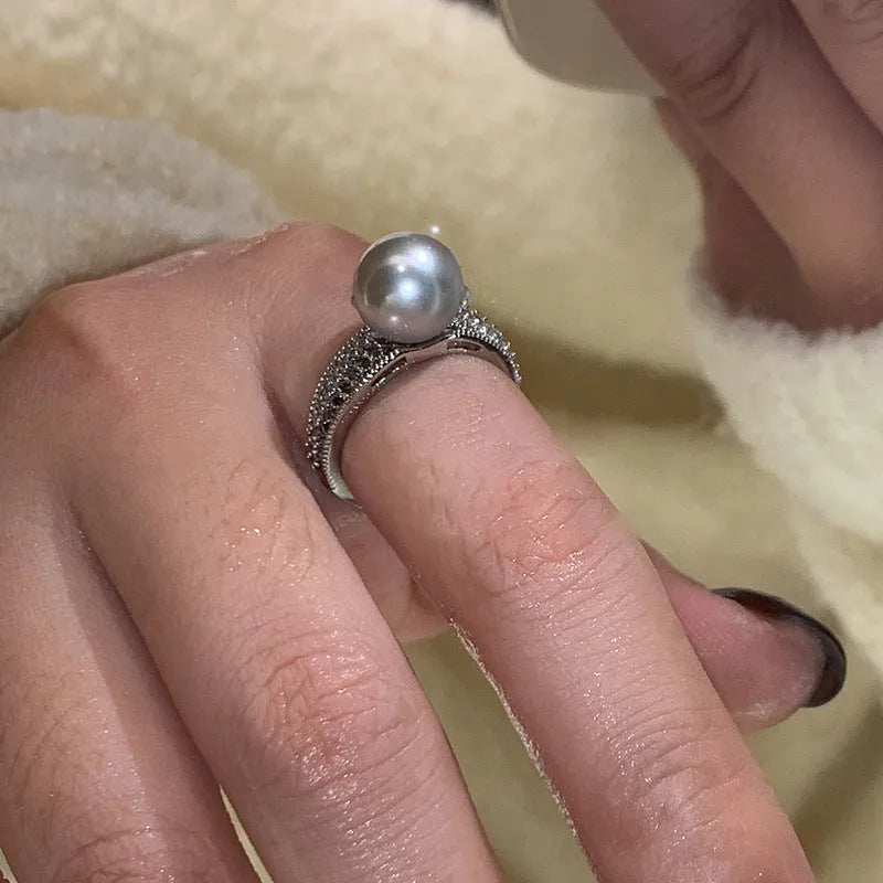 Geometric copper open ring with a black pearl on a model's finger.