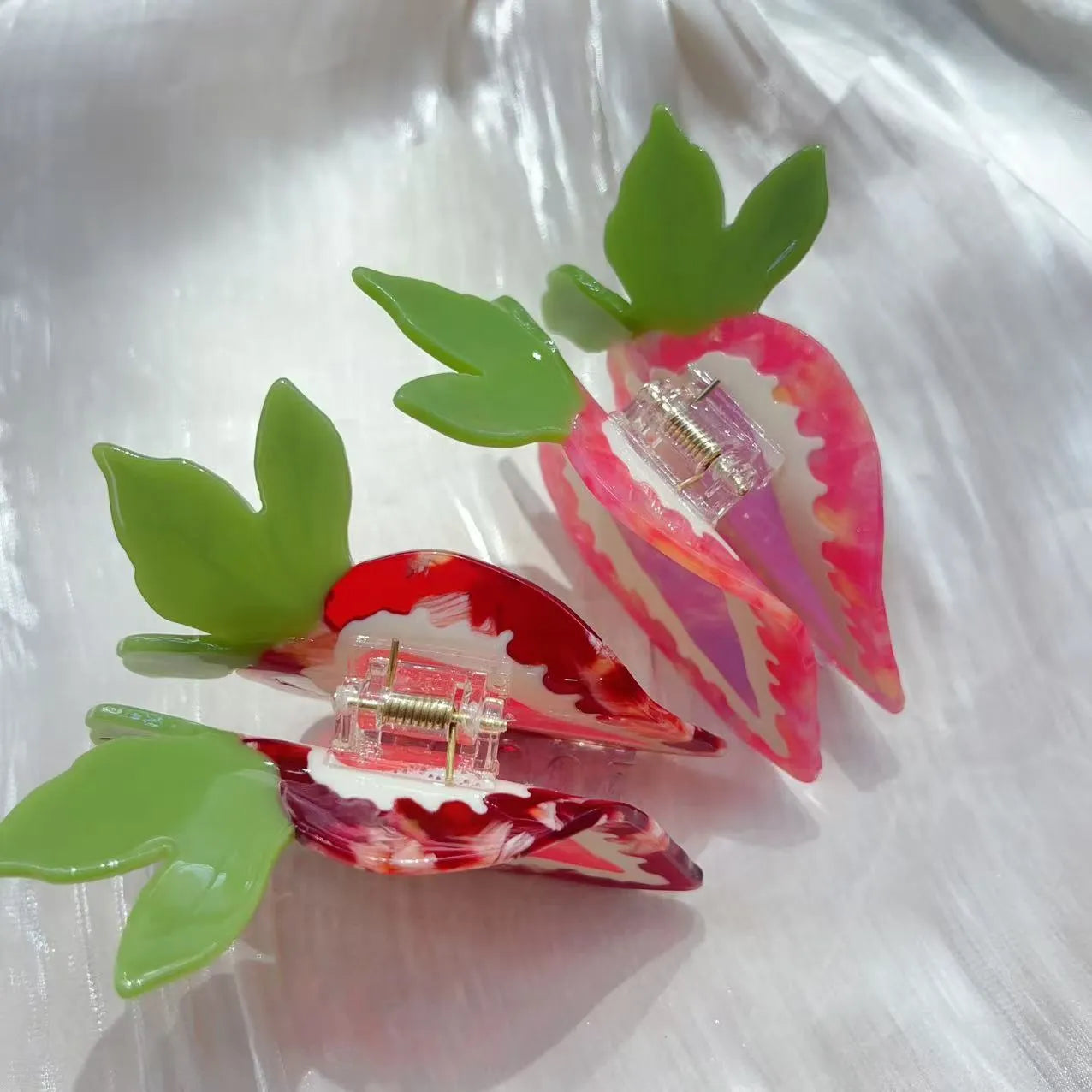 A close-up of a handmade strawberry-shaped hairpin in either red or pink colour on a light background.