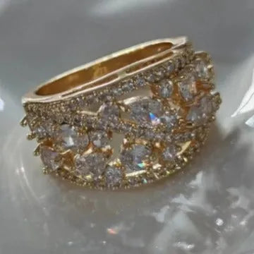Women's hollow round fashion ring in gold and platinum finishes with blue and white stone accents.