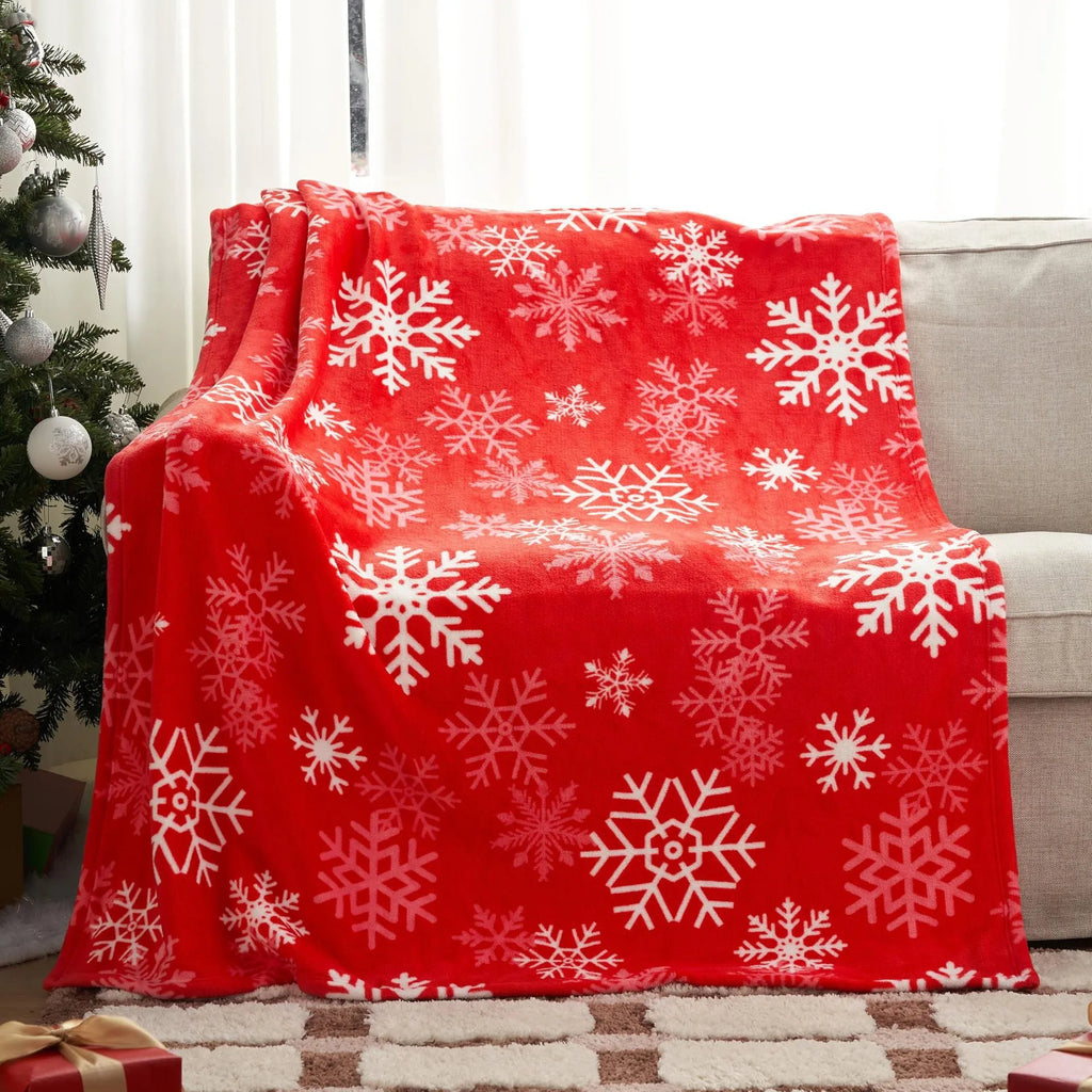 Soft red plush Christmas blanket draped over a sofa, showing its textured flannel fabric.