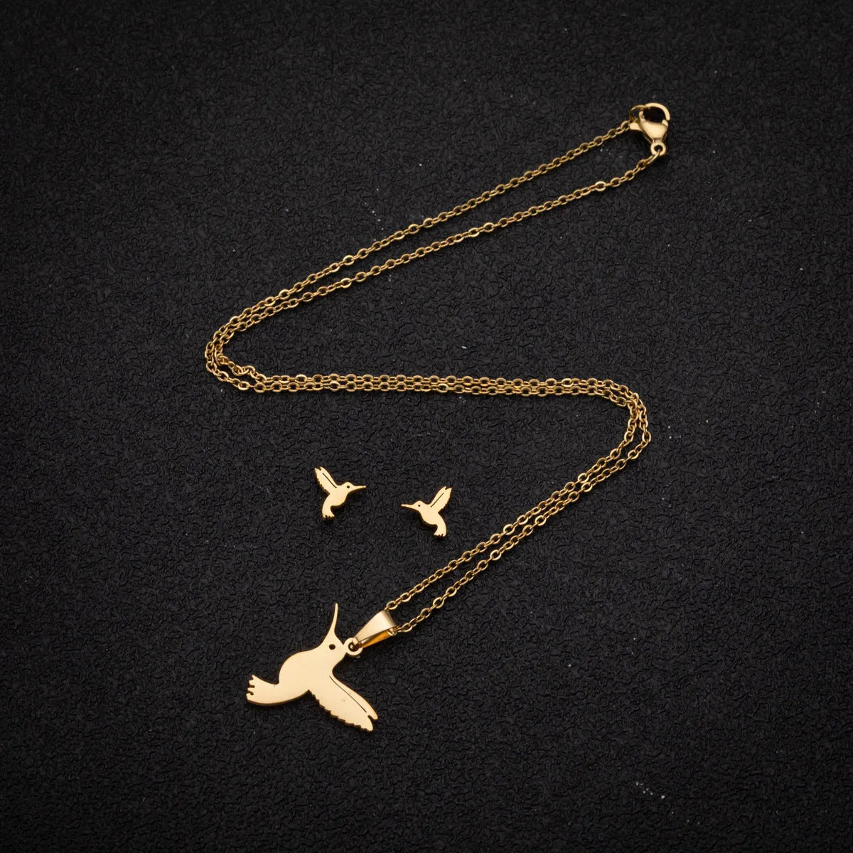 Cute little animal stainless steel jewellery set with bird motif necklace and earrings in gold colour on a white background
