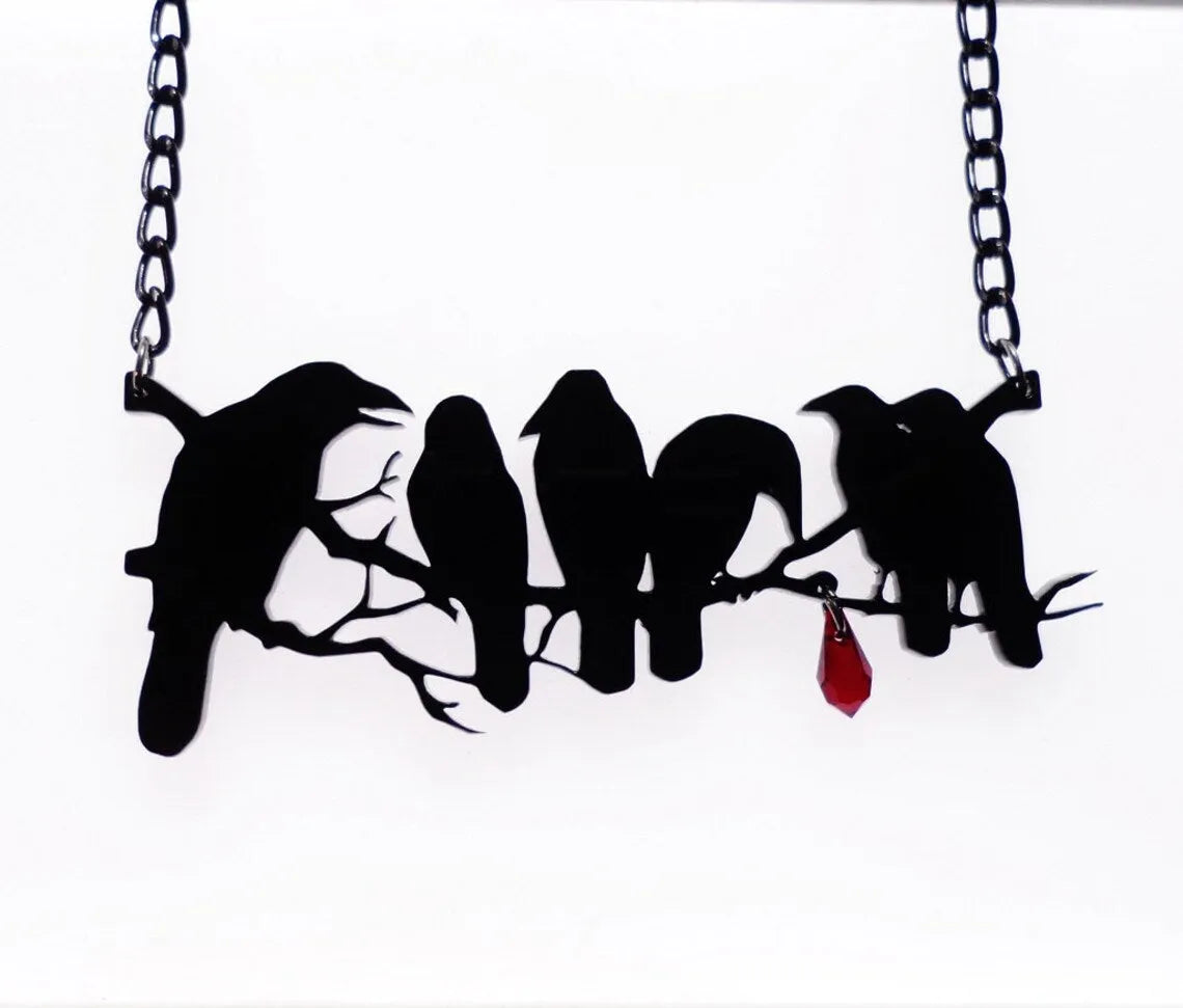 Black Gothic crow necklace with electroplated finish and cross chain on dark background