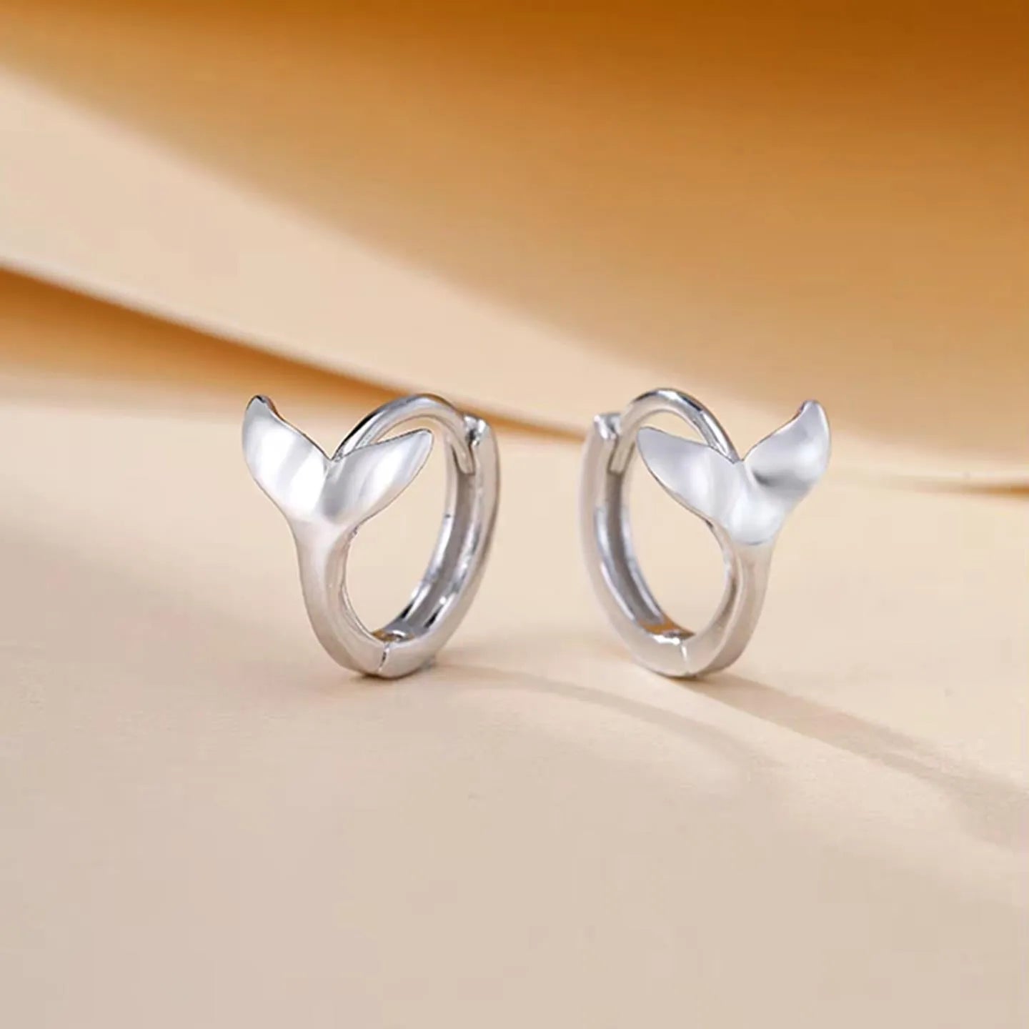 A pair of simple women's fishtail earrings with an electroplated metallic finish.