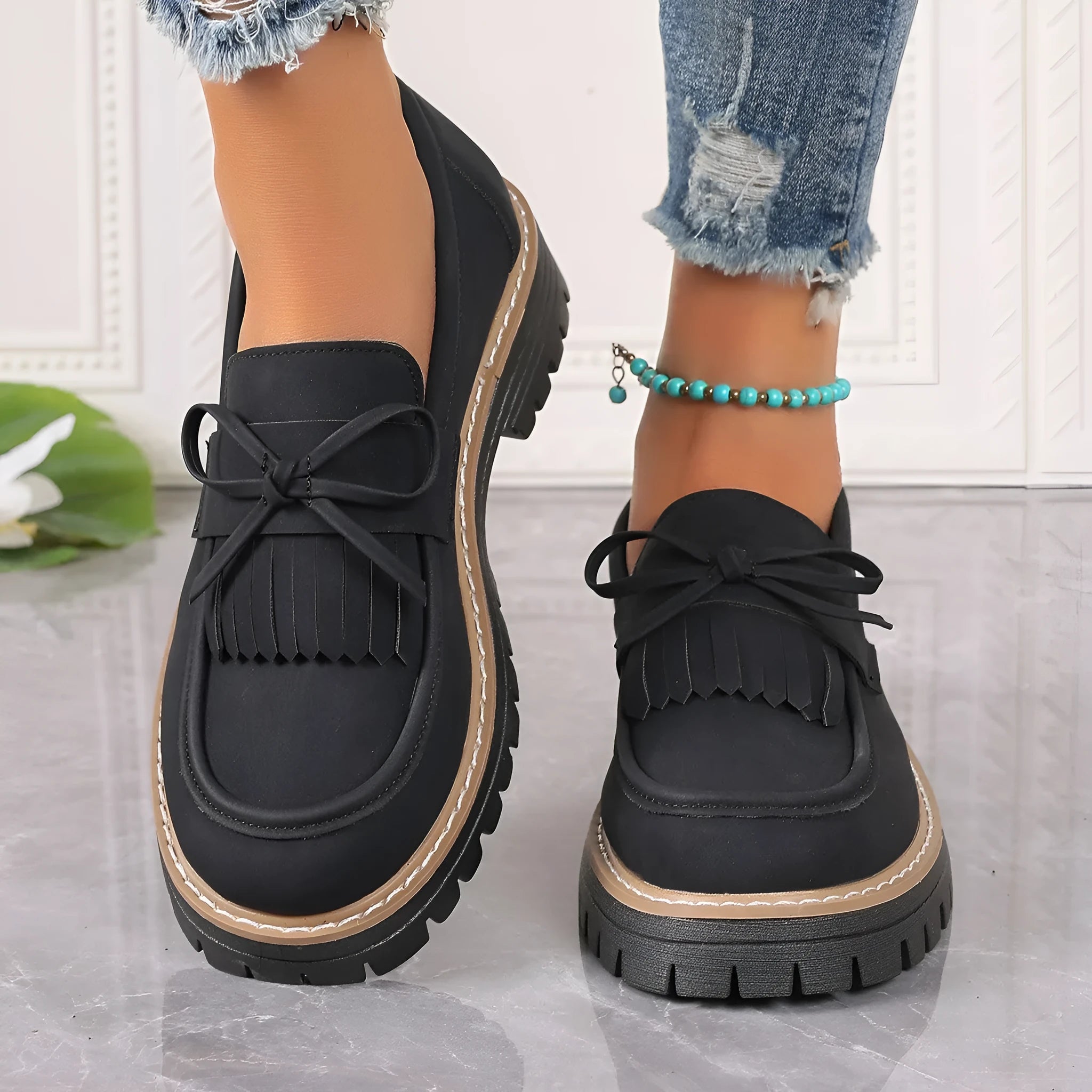 Women's black plus size loafers with a bowknot, tassel, and chunky rubber sole.