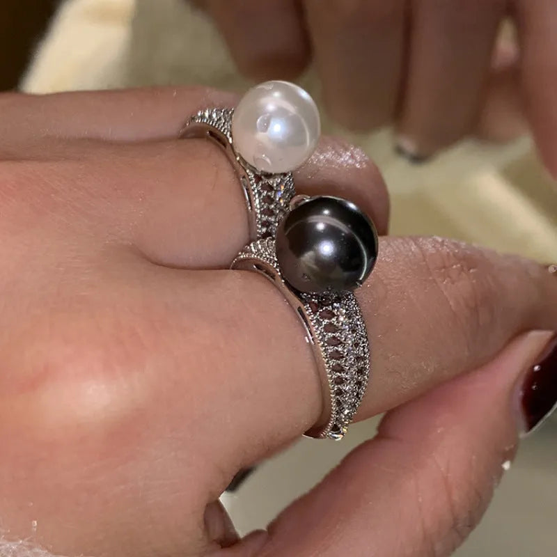 Geometric copper open ring with a black pearl on a model's finger.