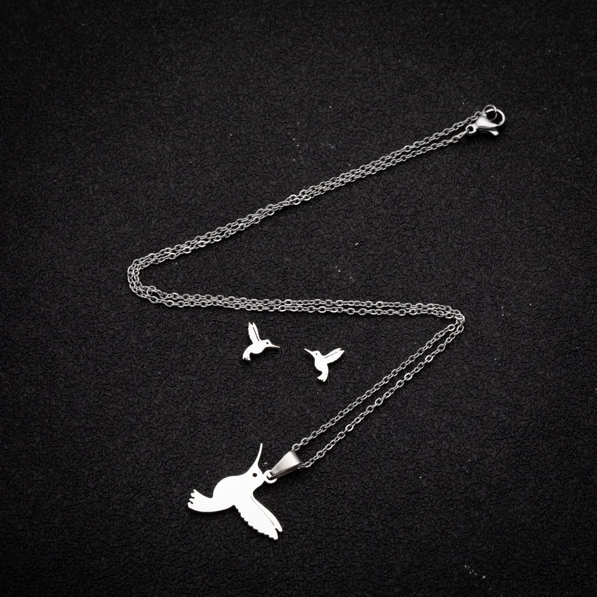 Cute little animal stainless steel jewellery set with bird motif necklace and earrings in gold colour on a white background