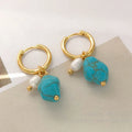 A pair of long dangle earrings with an irregular turquoise geometric clip and a cultured pearl drop on a copper setting.