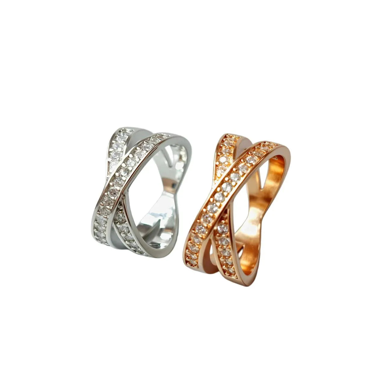 A silver or rose gold plated metal ring with a cross design and small zircon stones, shown on a finger.