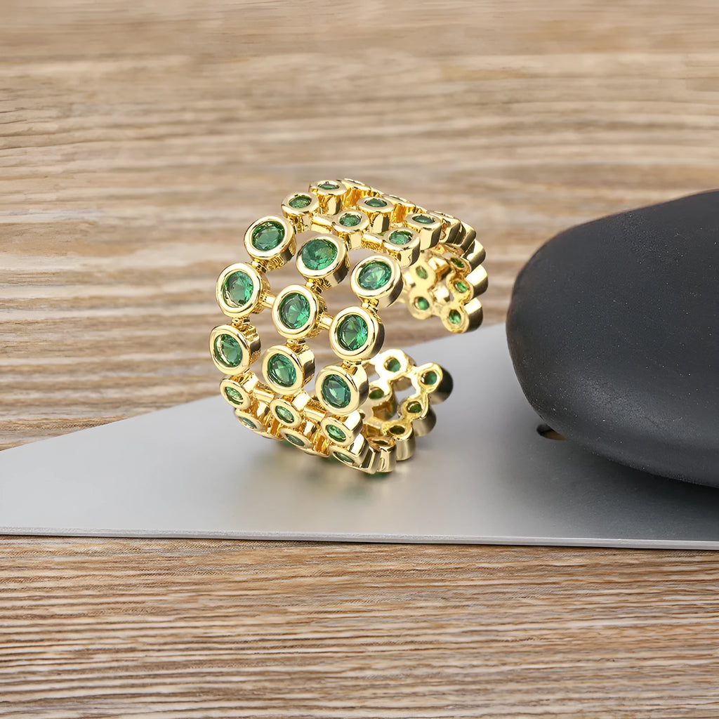 Copper ring with gold plating showing three-layer green stone setting and zircon detailing on wide band.