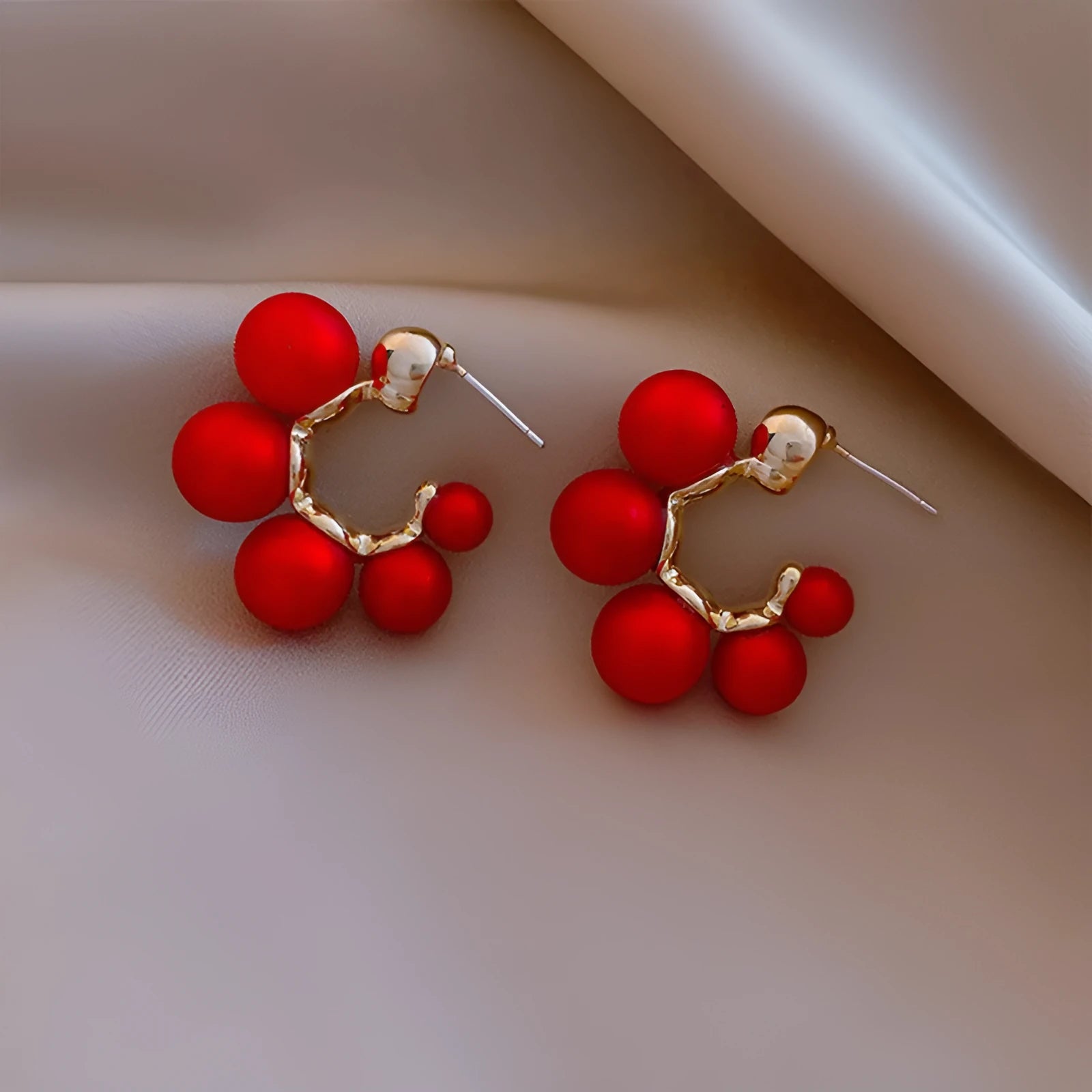 A pair of red bell-shaped alloy earrings for women next to a pair of plain white alloy earrings.
