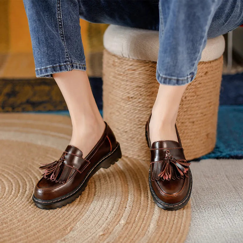 Women's brown leather loafers with tassel detail and a low chunky heel.