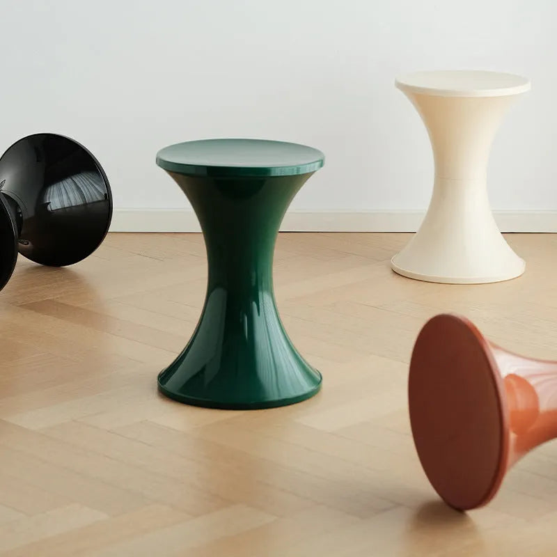 Green plastic hourglass-shaped shoe changing stool on a wooden floor.