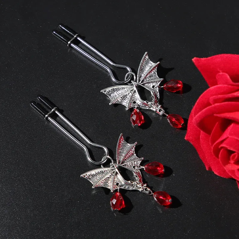 Silver alloy bat-themed nipple clamp with adjustable pressure and a red ruby decorative clip.