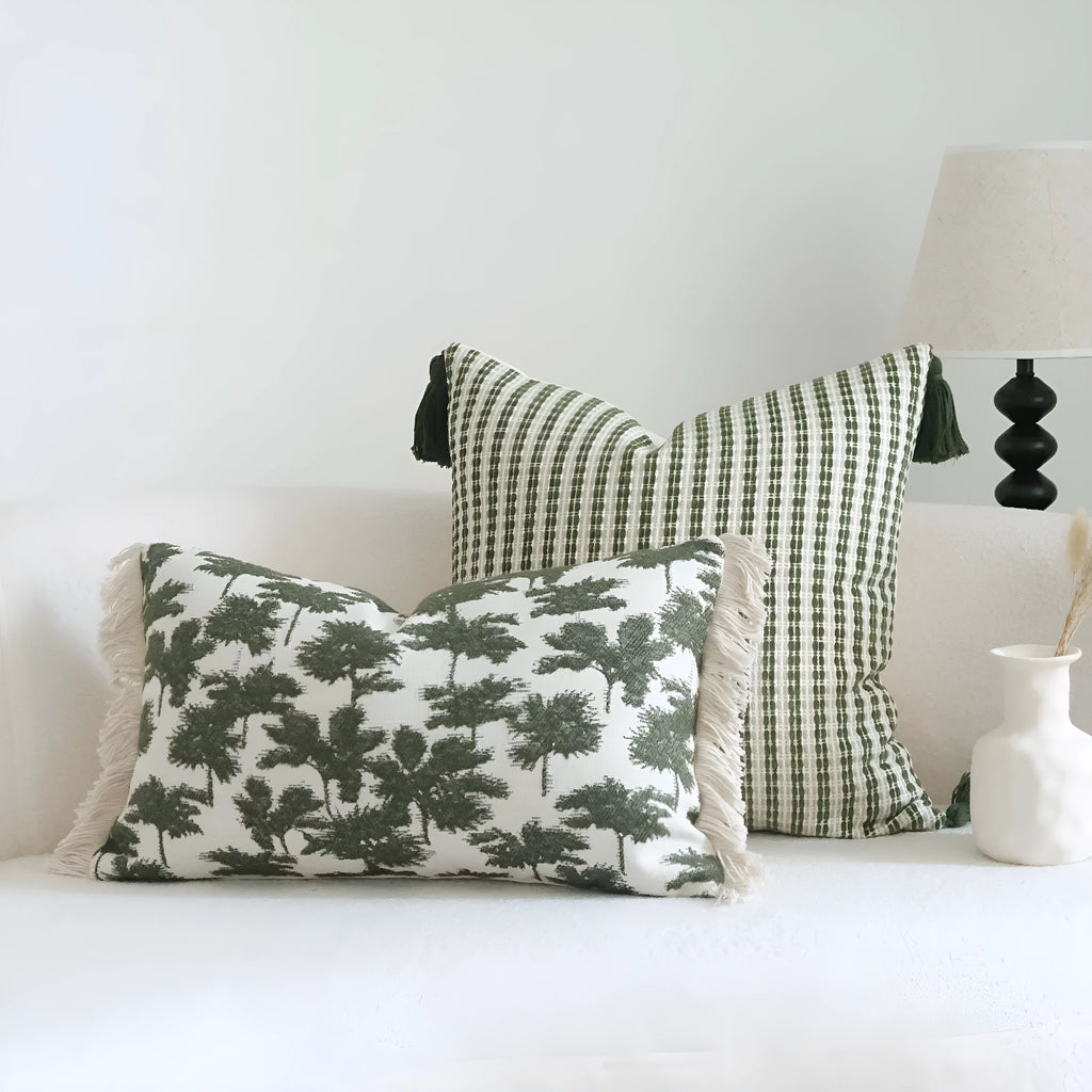 Green cotton and linen hotel sample pillow with botanical pattern and tassel detail on a display bed.