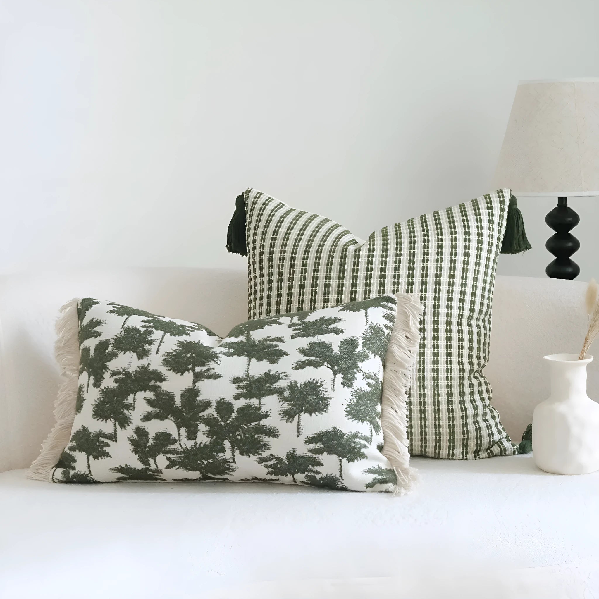 Green cotton and linen hotel sample pillow with botanical pattern and tassel detail on a display bed.