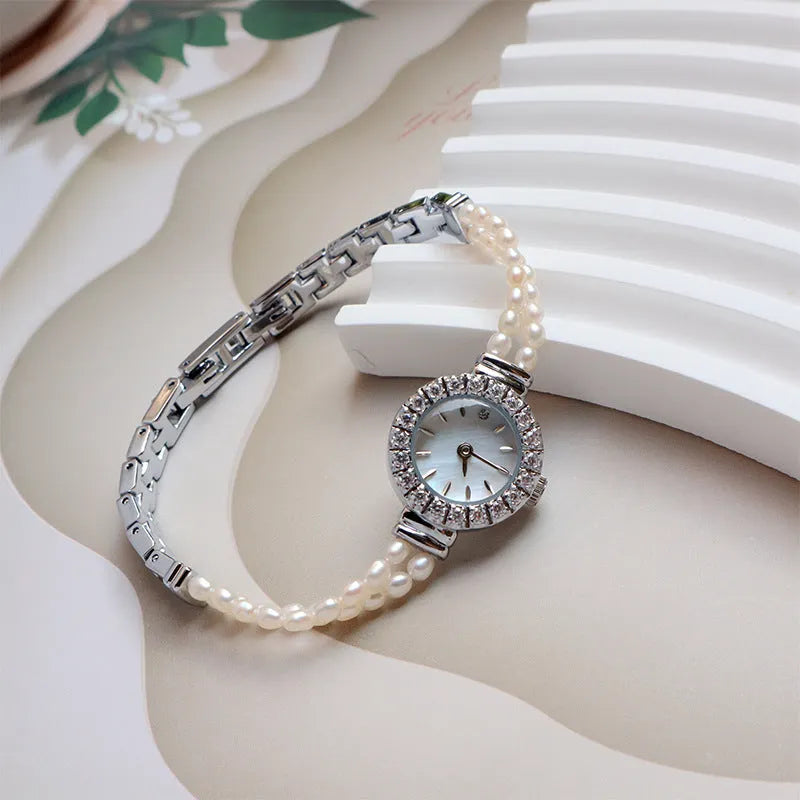 Women's light gold bracelet watch with a freshwater pearl charm and round mineral glass dial.