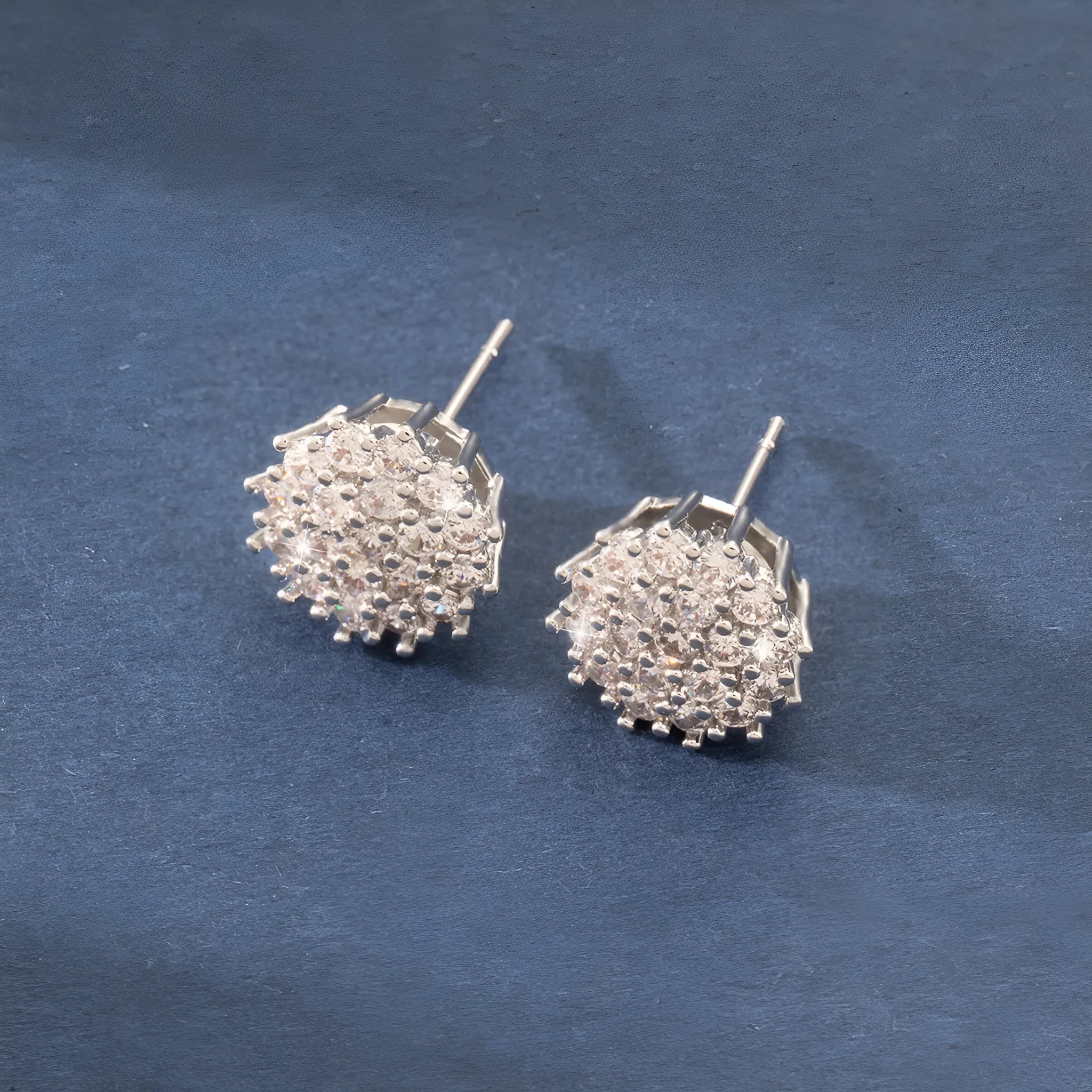 Pair of copper electroplated stud earrings in silver with irregular and round shapes on white background