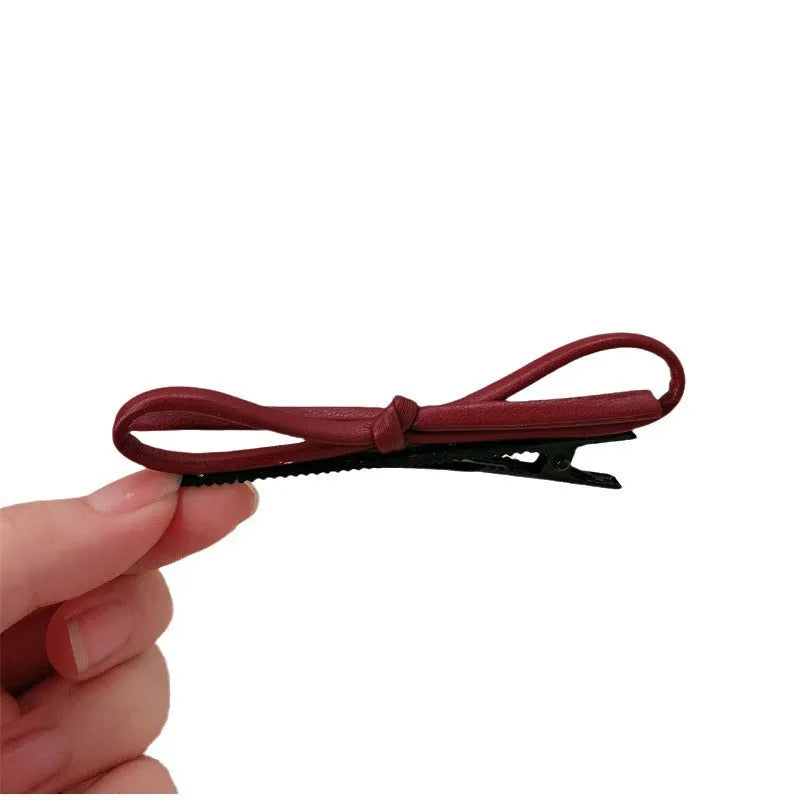 Wine red genuine leather bow hair barrette with a 6cm long metal clip on a white background.