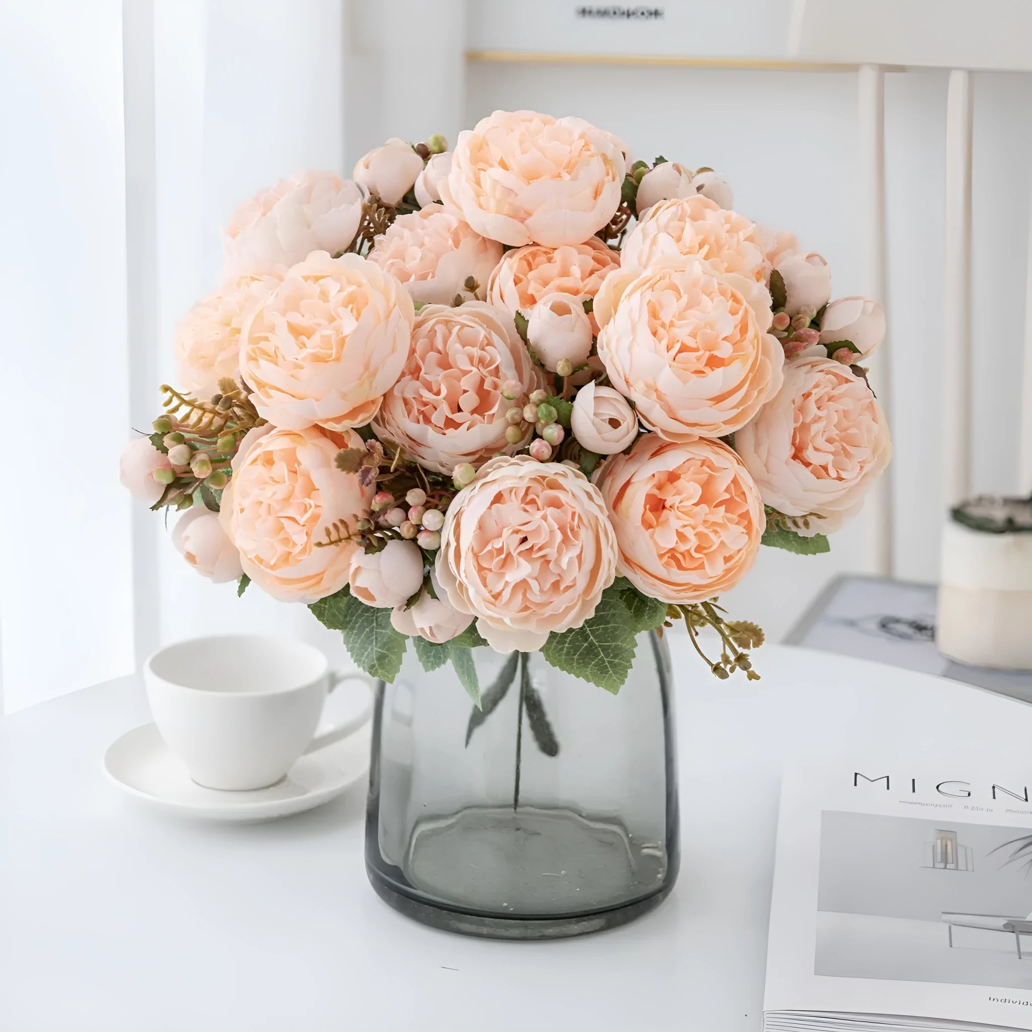 Artificial silk peony bouquet in a vase with champagne coloured blooms and green leaves