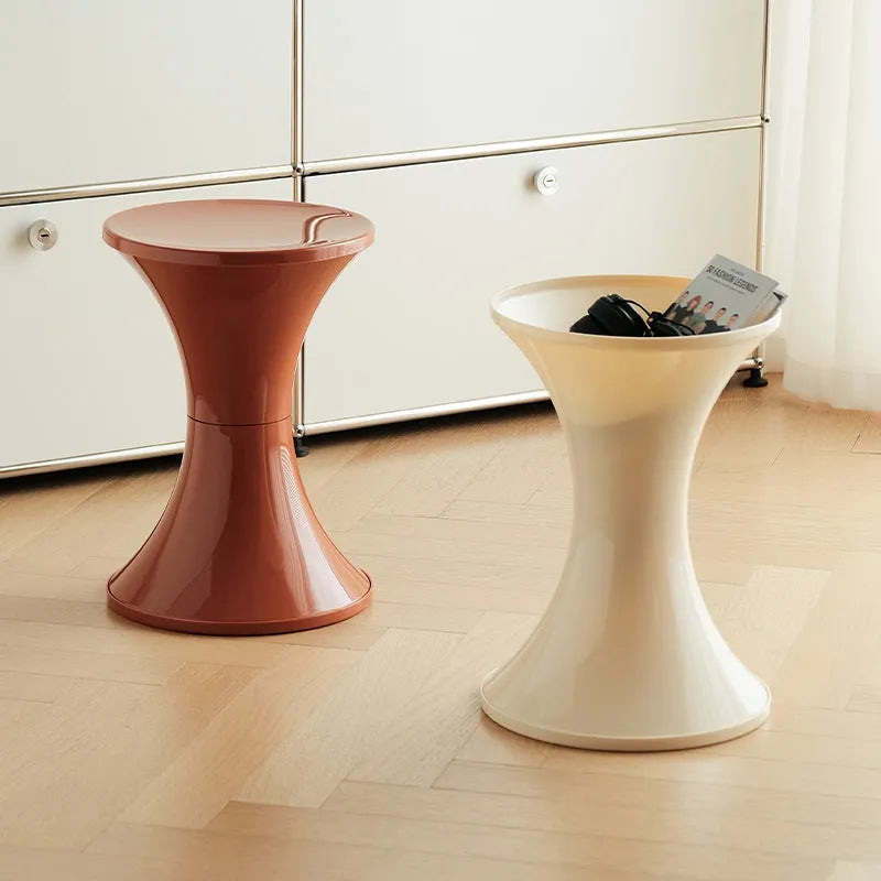 Green plastic hourglass-shaped shoe changing stool on a wooden floor.