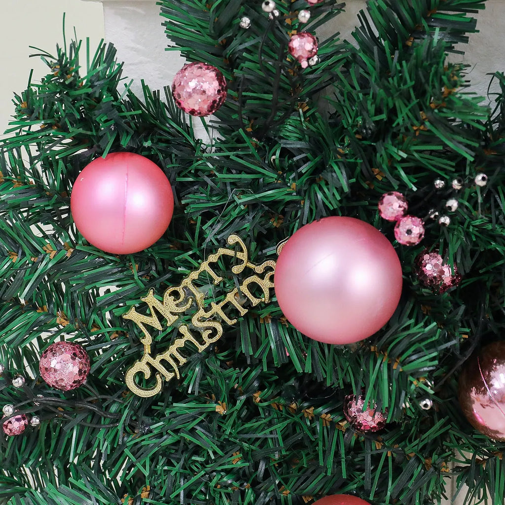 Long pink Christmas rattan garland with small decorative fruits and warm white LED lights draped on a mantelpiece.