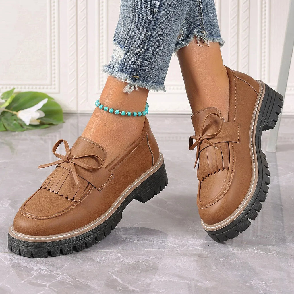 Women's black plus size loafers with a bowknot, tassel, and chunky rubber sole.