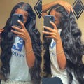 A black synthetic front lace wig with long curly hair and side-swept bangs, displayed on a wig stand.