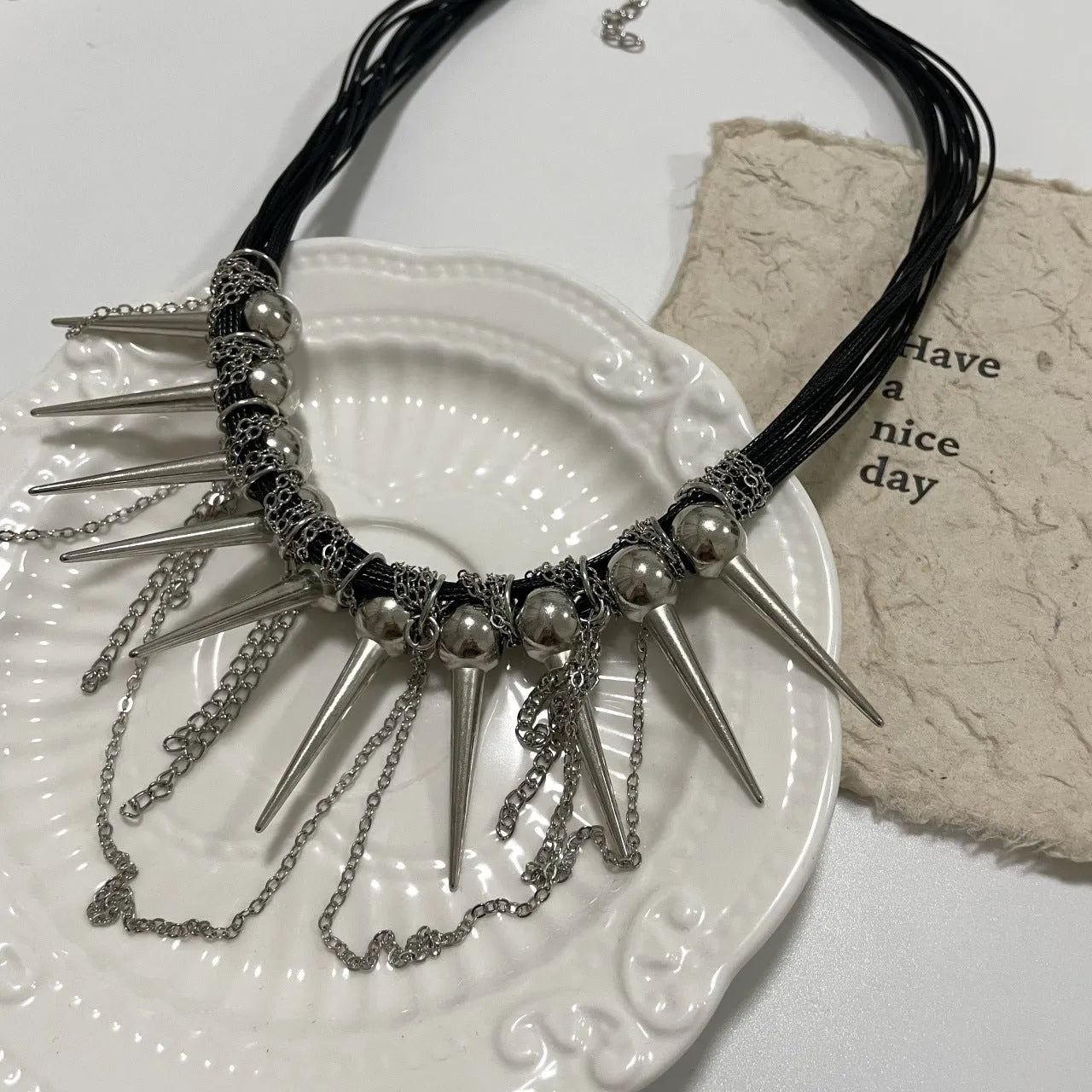 Leather necklace with electroplated round beads, winding design, tassel, and point rivet details.