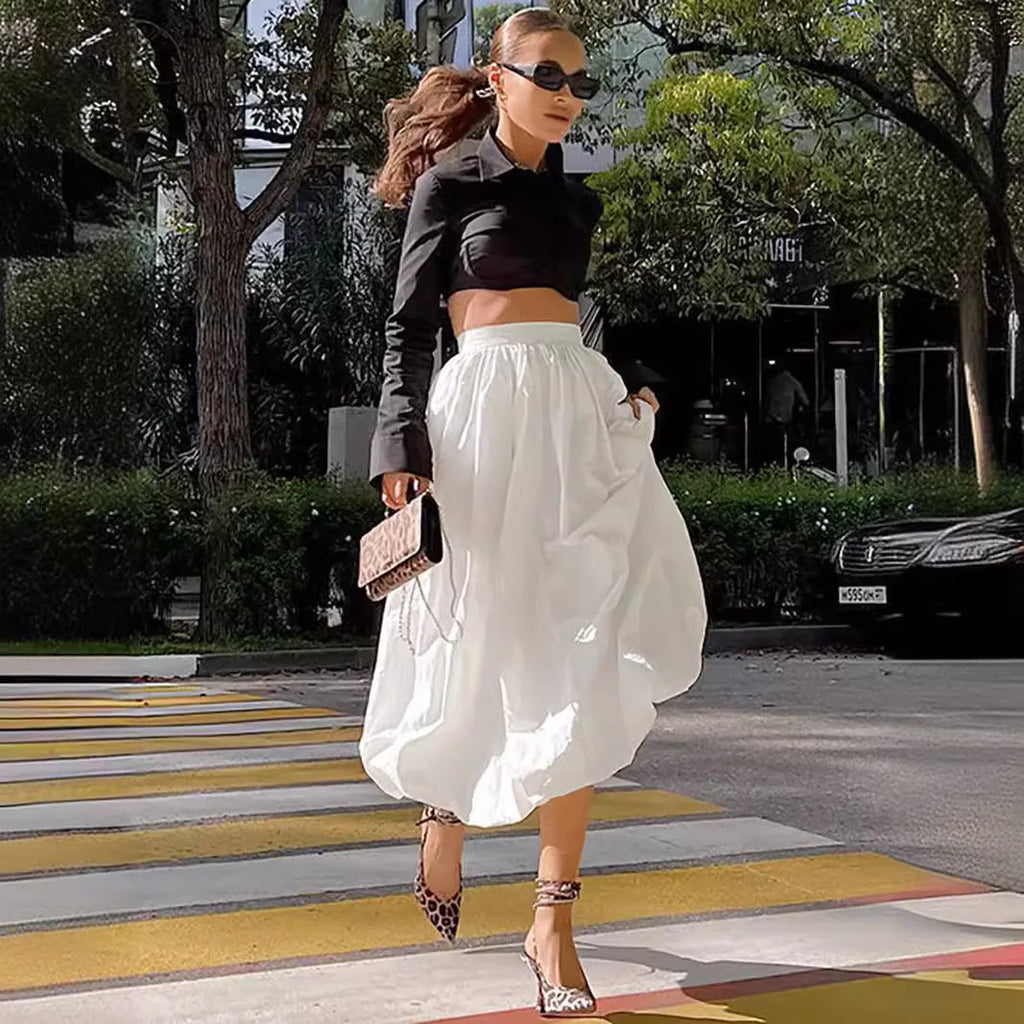 Women's solid colour long cotton skirt on a hanger, available in black and white.