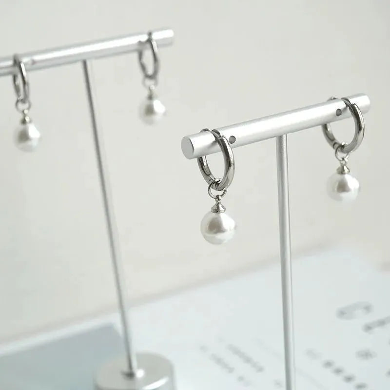Geometric women's pearl drop earrings with alloy frame and titanium steel fittings.