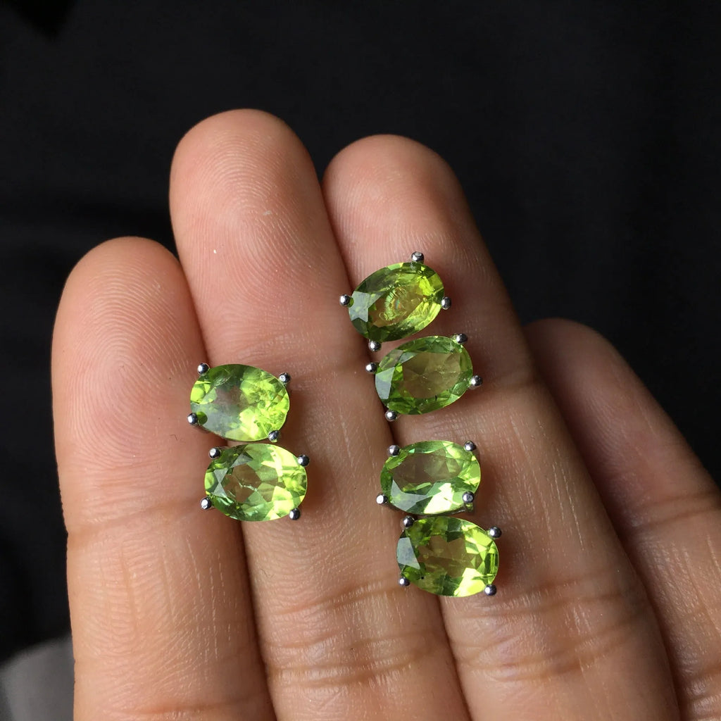 Close-up of natural grass green olivine stud earrings in sterling silver geometric setting.