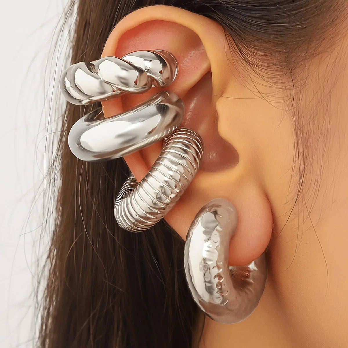 Set of four geometric gold and silver tone clip-on earrings for women on a flat lay.