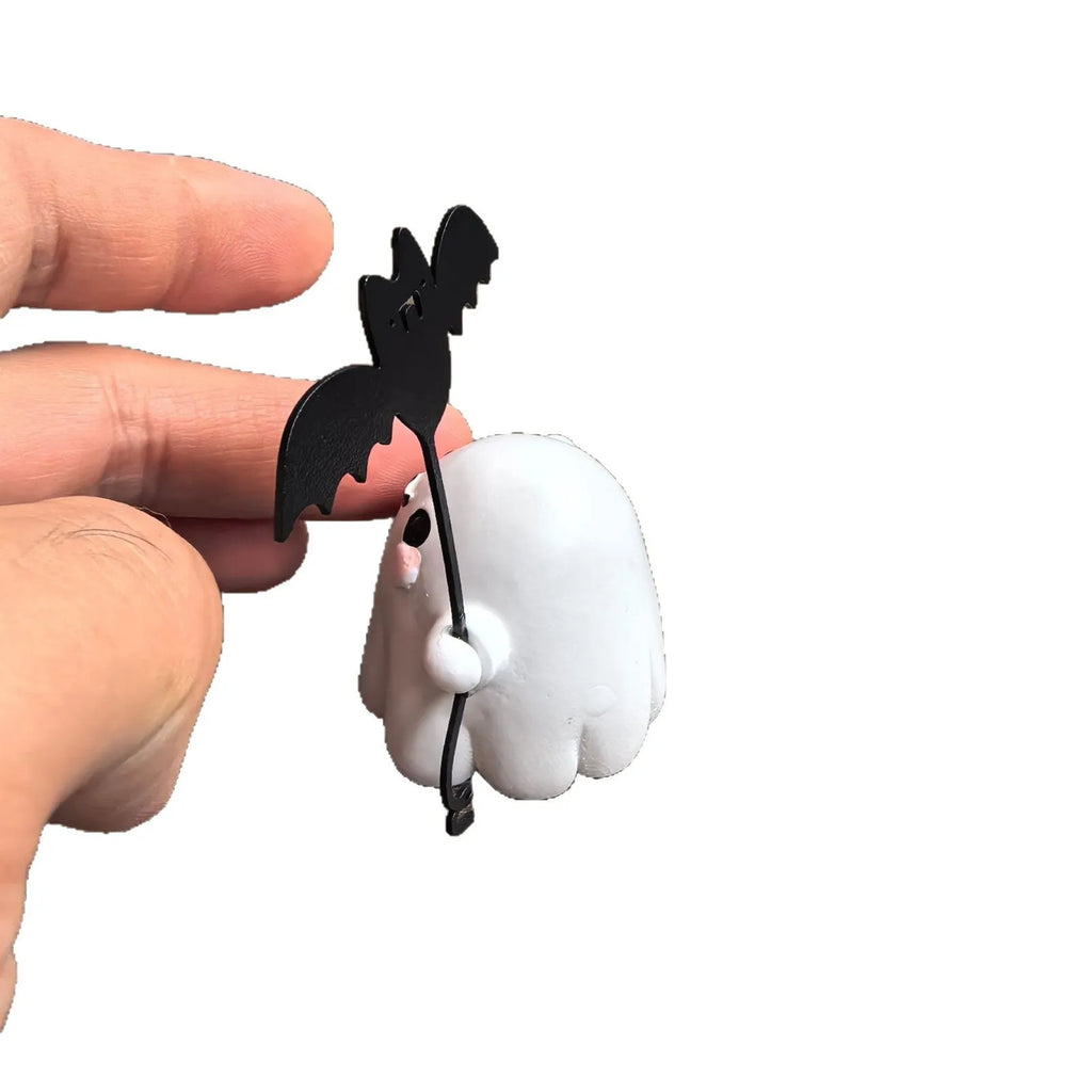 Small white ghost walking a dog and holding a bat, resin Halloween statue on a wooden surface.
