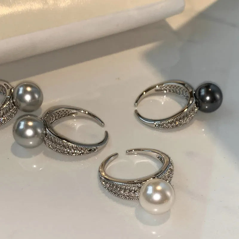 Geometric copper open ring with a black pearl on a model's finger.