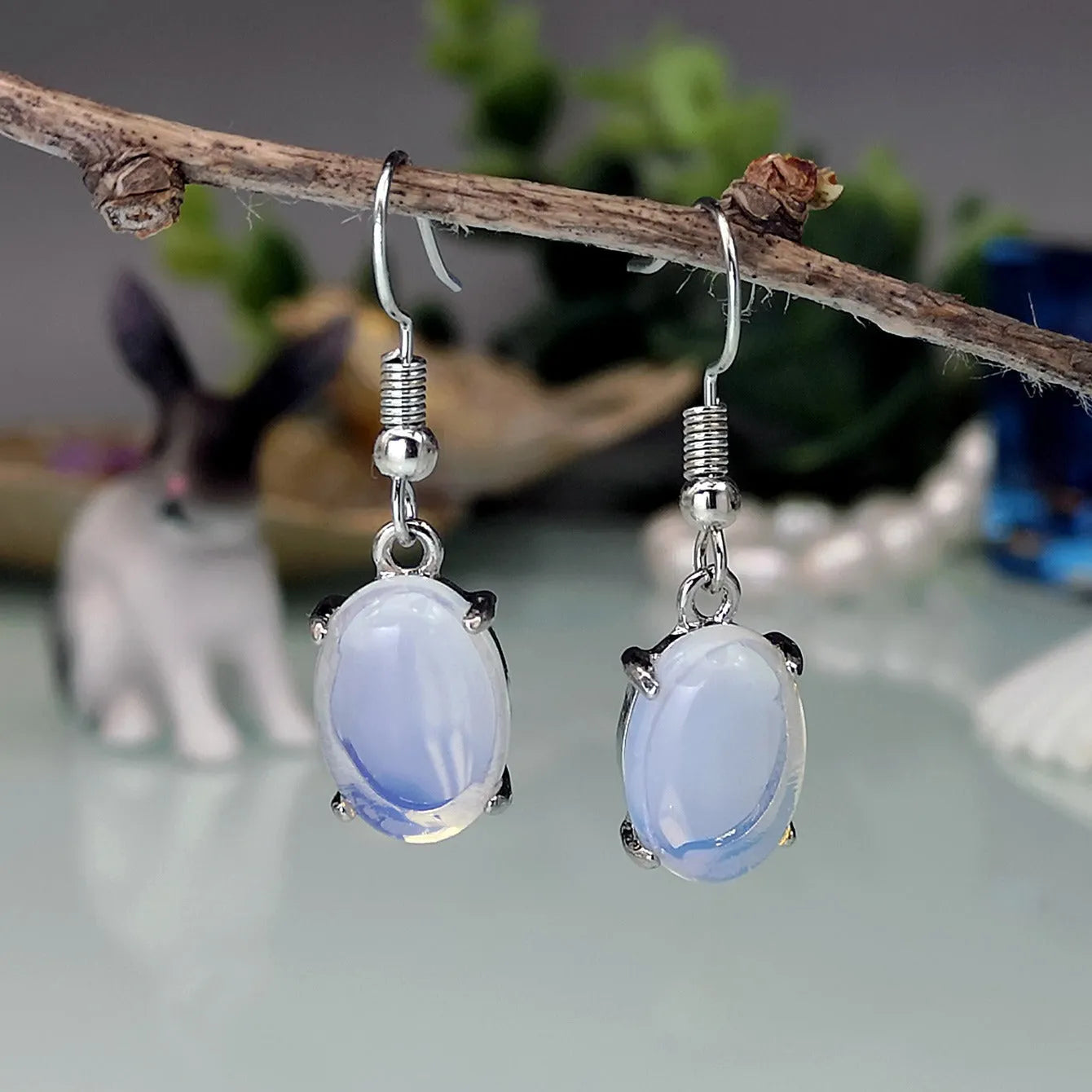 A pair of opal drop earrings with a retro moonstone design and electroplated alloy finish in a moonlight white colour.