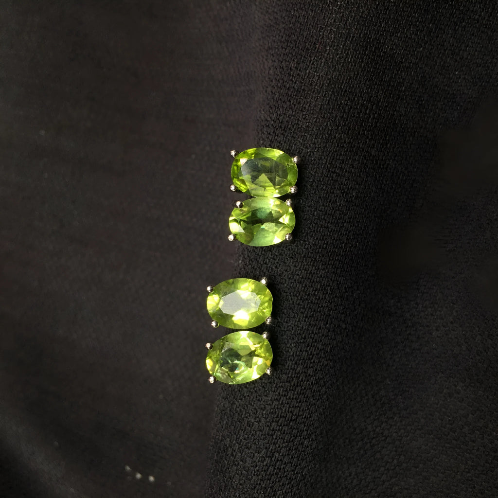 Close-up of natural grass green olivine stud earrings in sterling silver geometric setting.