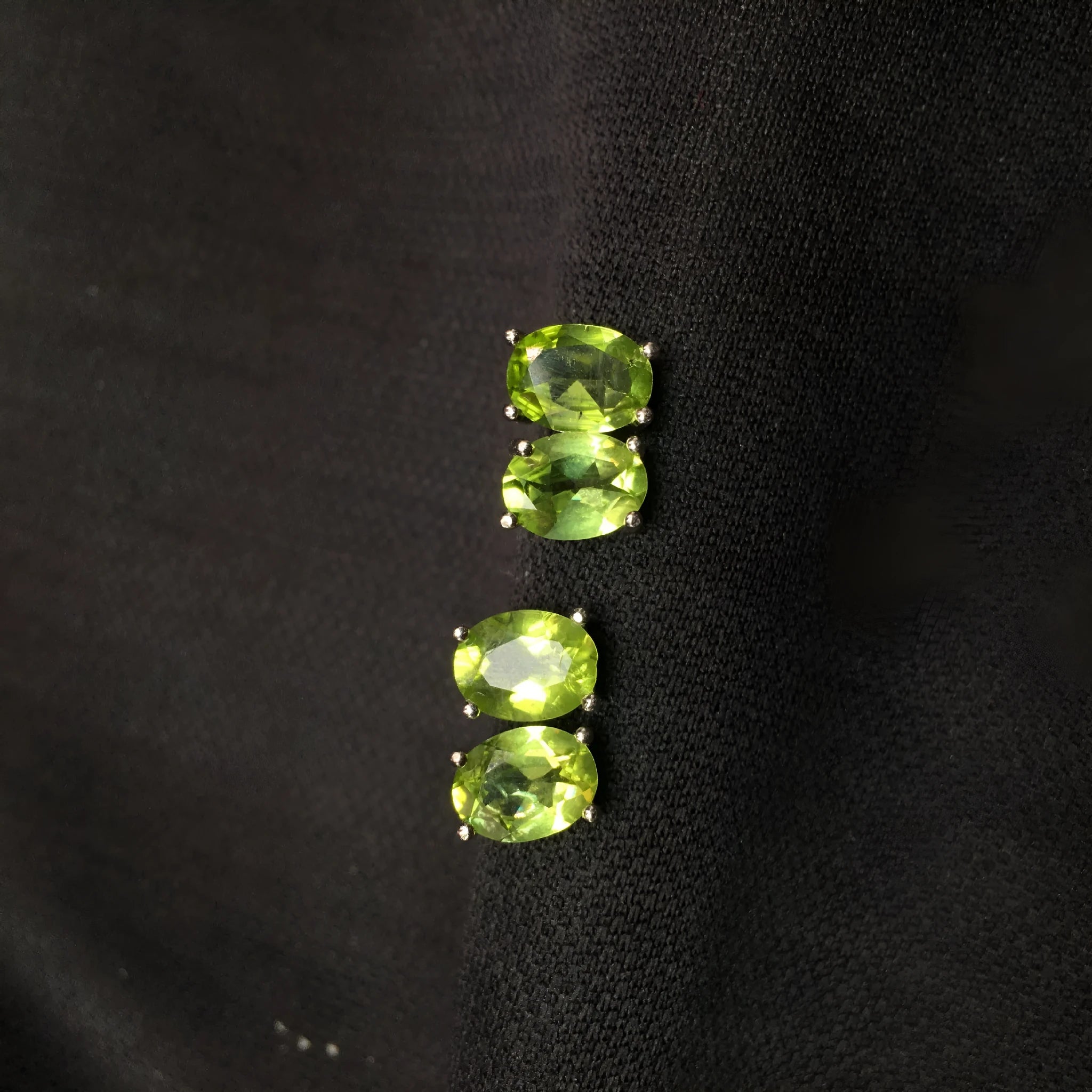 Close-up of natural grass green olivine stud earrings in sterling silver geometric setting.