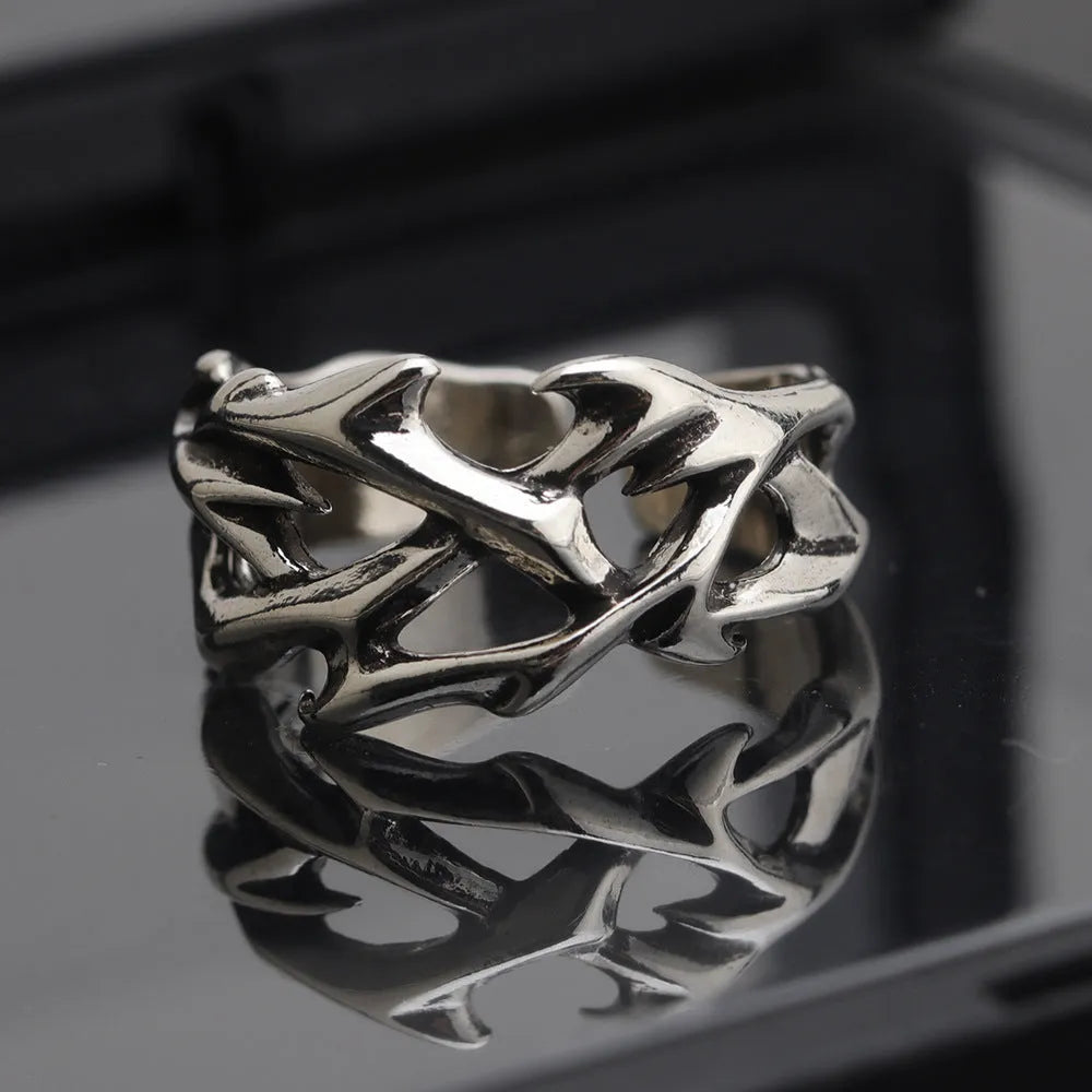 Copper geometric thorn and flower design ring with an adjustable opening on a dark background.