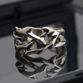 Copper geometric thorn and flower design ring with an adjustable opening on a dark background.