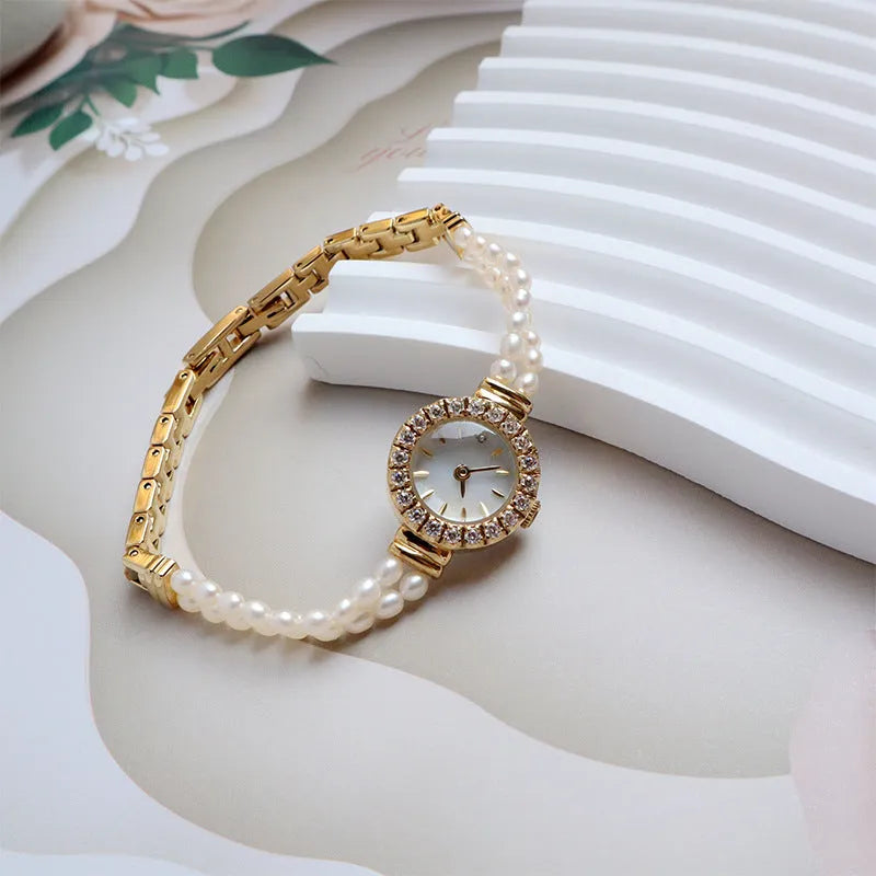 Women's light gold bracelet watch with a freshwater pearl charm and round mineral glass dial.