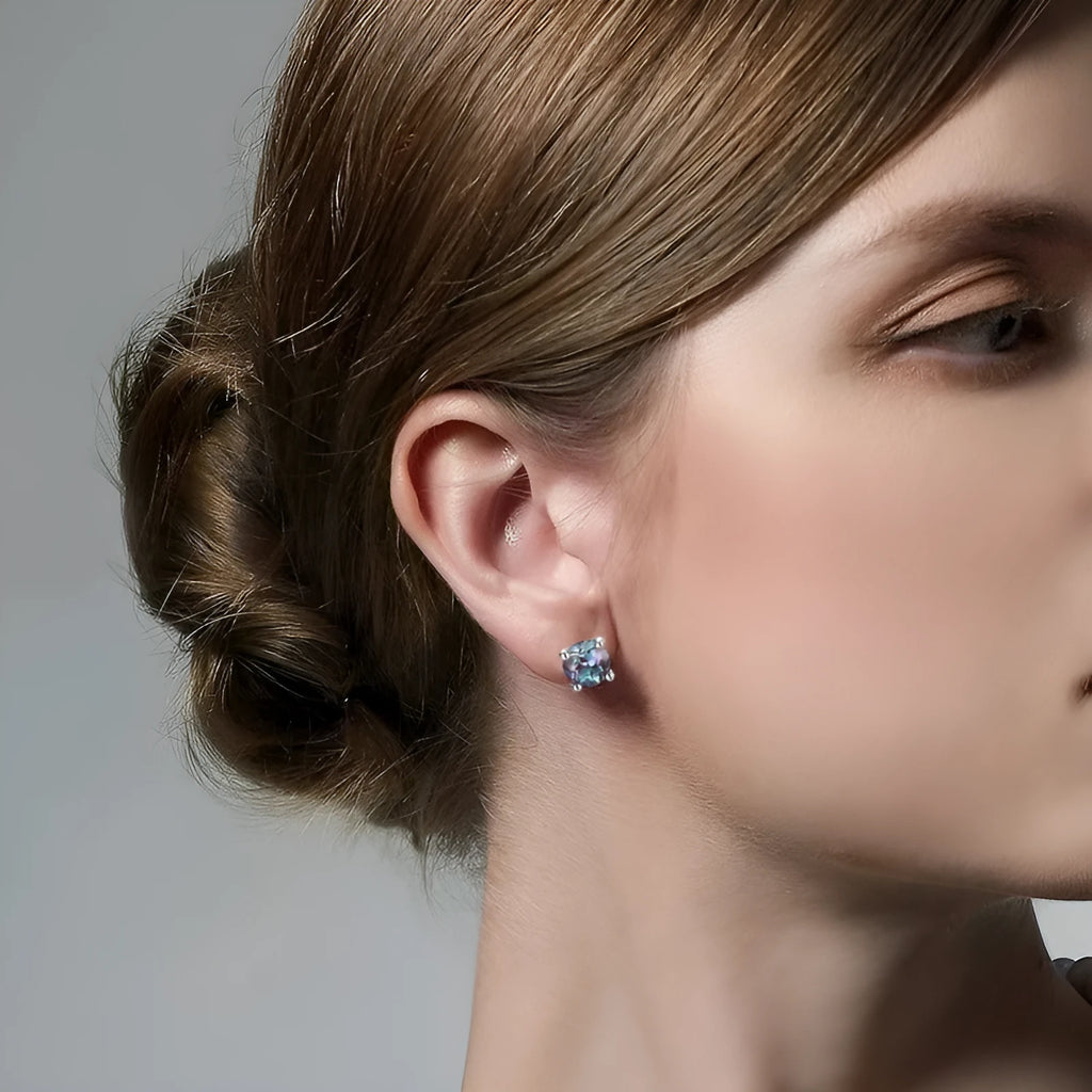 A pair of simple geometric silver ear studs with a round cultivated Alexandrite stone.