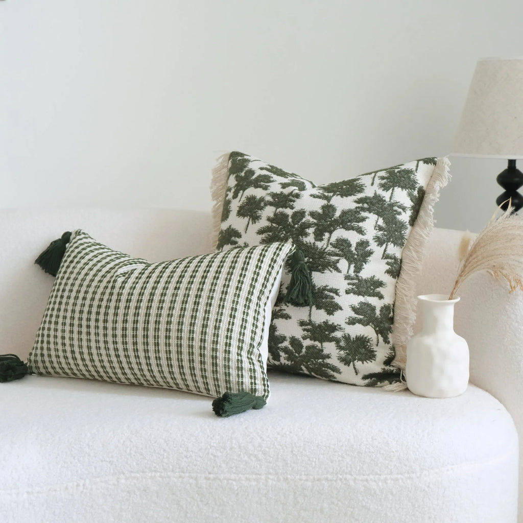Green cotton and linen hotel sample pillow with botanical pattern and tassel detail on a display bed.