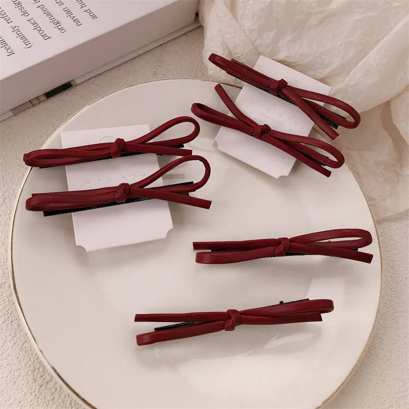 Wine red genuine leather bow hair barrette with a 6cm long metal clip on a white background.