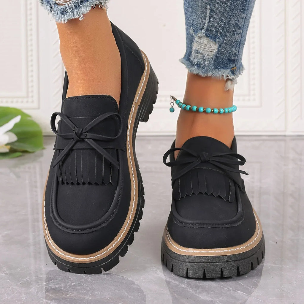 Women's black plus size loafers with a bowknot, tassel, and chunky rubber sole.