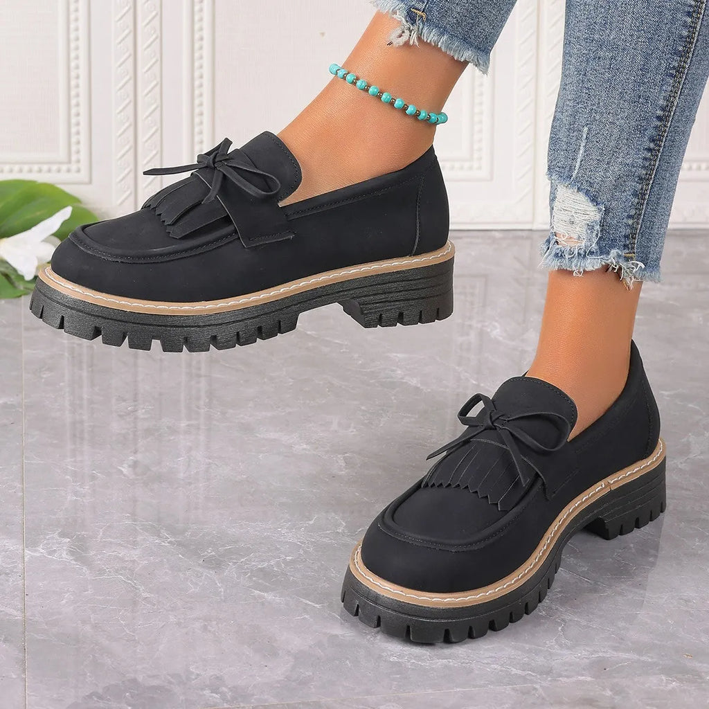 Women's black plus size loafers with a bowknot, tassel, and chunky rubber sole.
