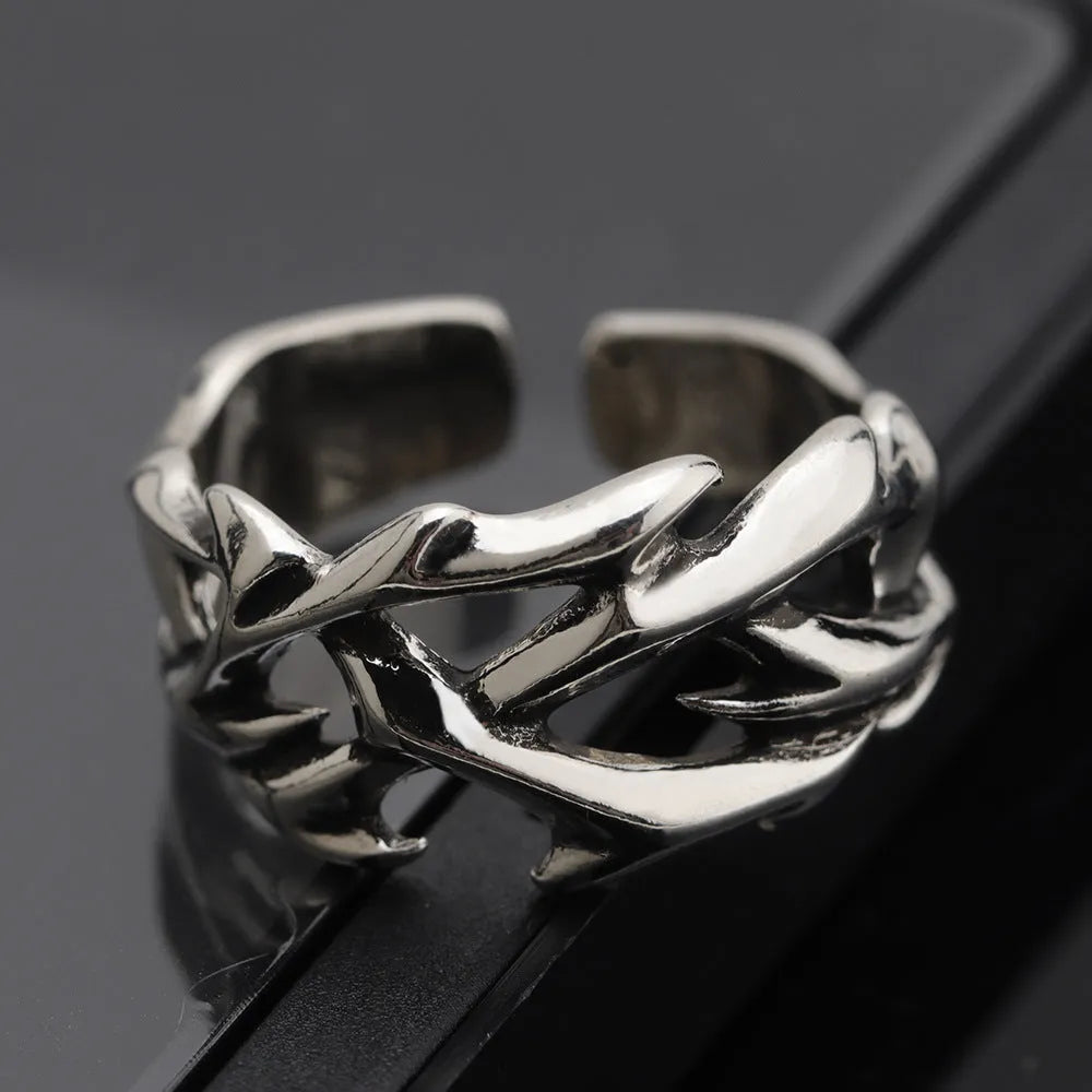 Copper geometric thorn and flower design ring with an adjustable opening on a dark background.