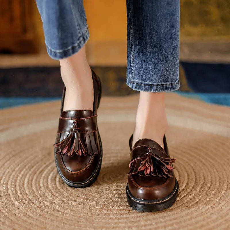 Women's brown leather loafers with tassel detail and a low chunky heel.