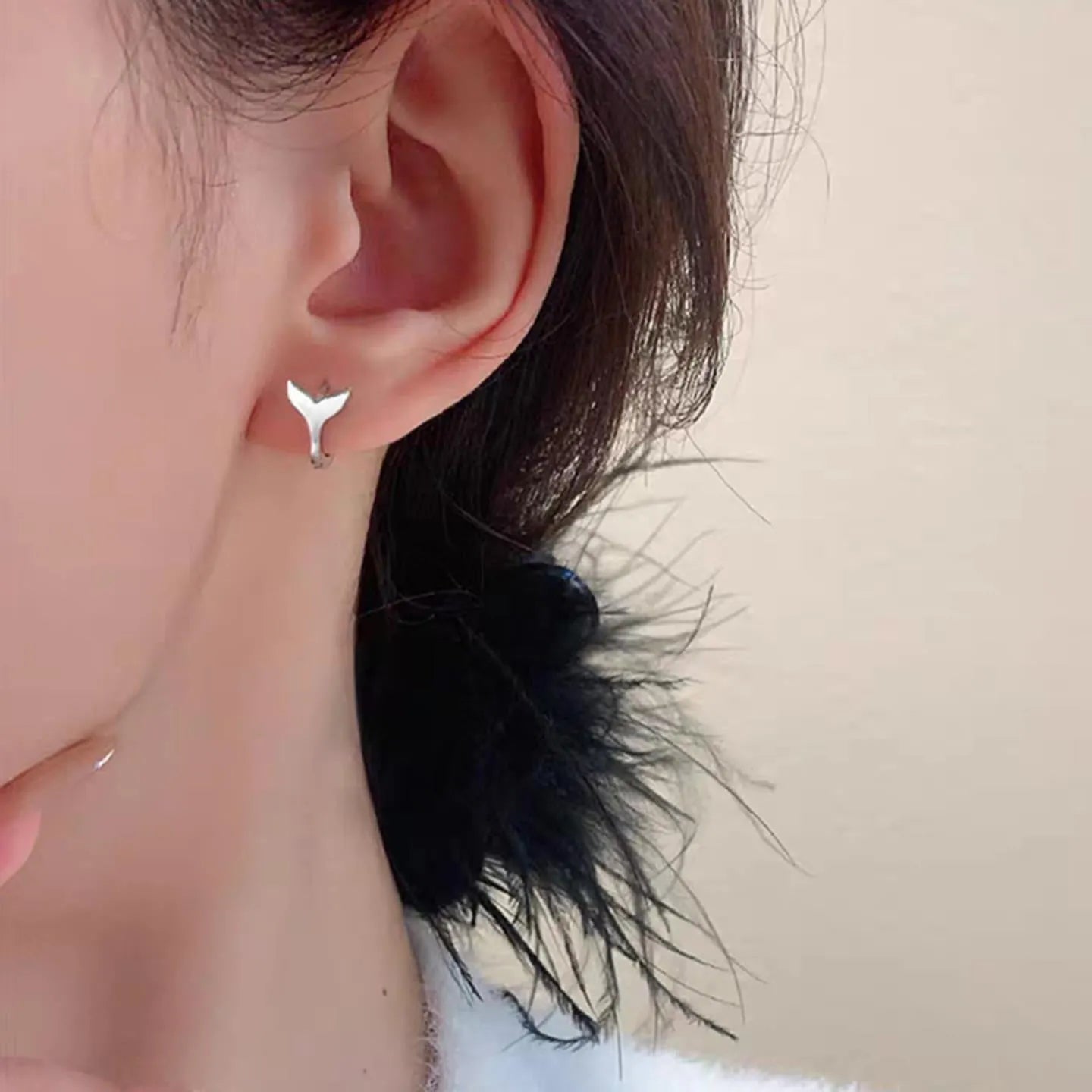 A pair of simple women's fishtail earrings with an electroplated metallic finish.